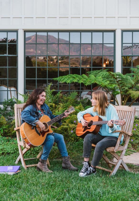 Dos mujeres sonriendo y tocando la guitarra.