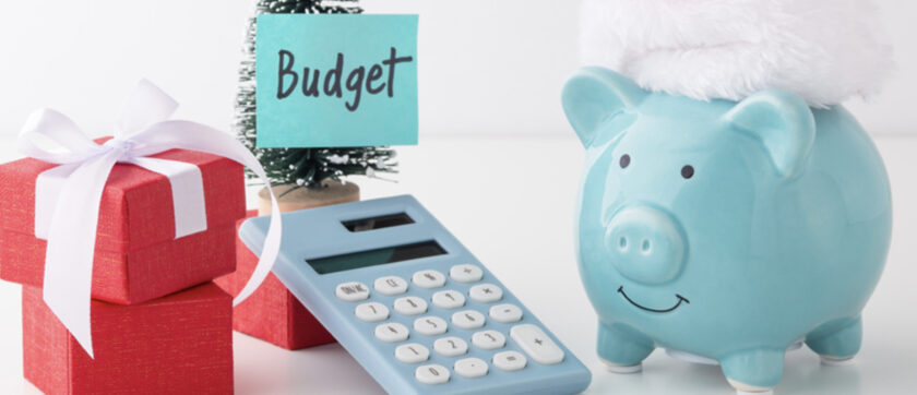 Piggy bank with Santa hat, gift boxes, and calculator for holiday savings and budgeting at Peninsula Credit Union.