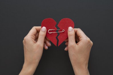 Two hands holding a felt heart held together with a safety pin