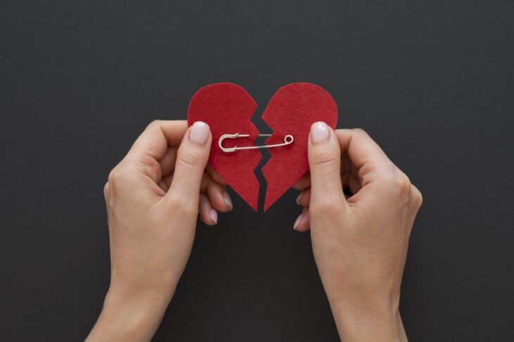 Two hands holding a felt heart held together with a safety pin