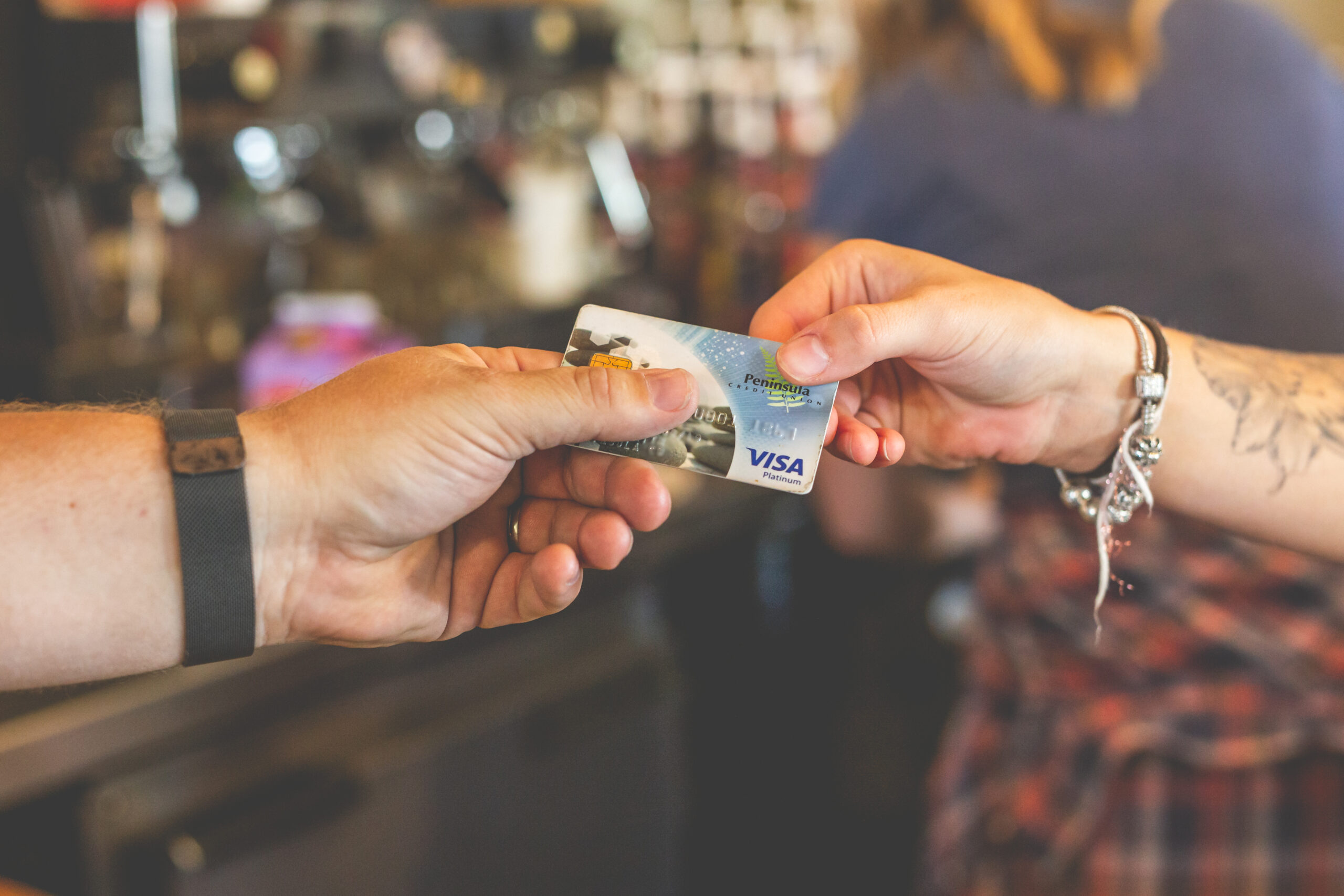 A person handing their debit card to a store clerk