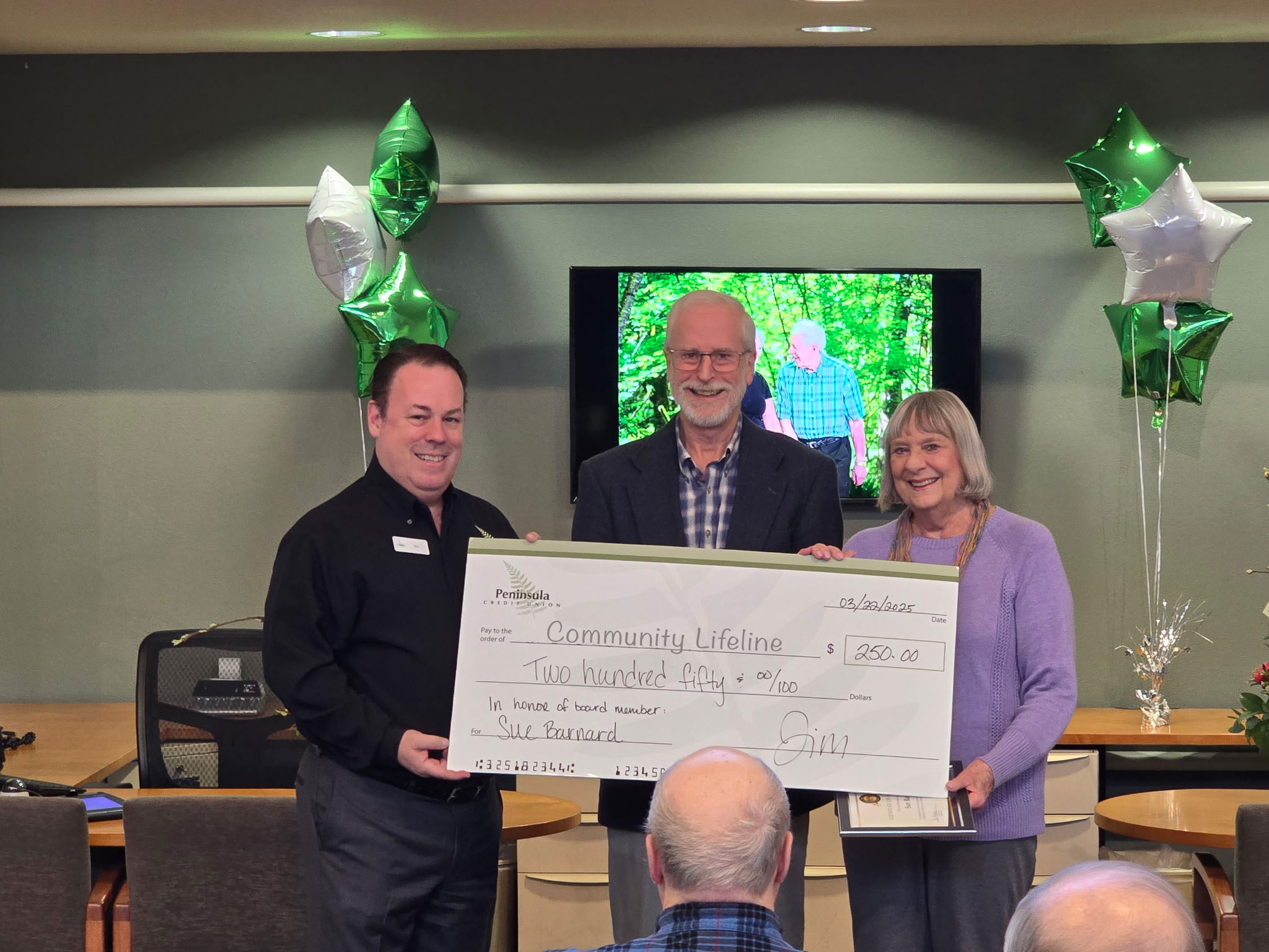 Jim Morrell, CEO, and John Bolender, Board Chair, present a check to Sue Barnard, retiring board member