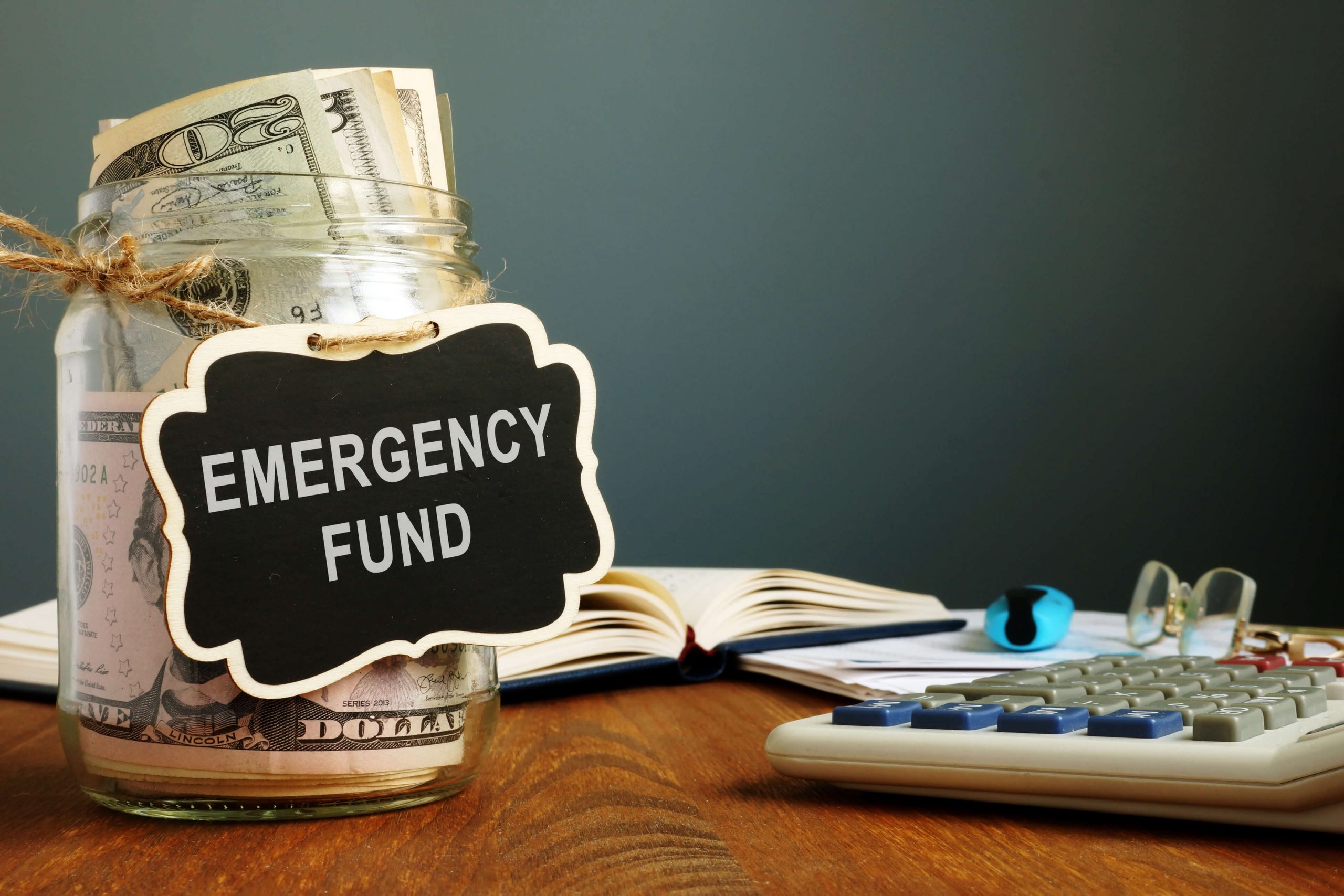 A jar full of money with a sign that says "Emergency Fund"