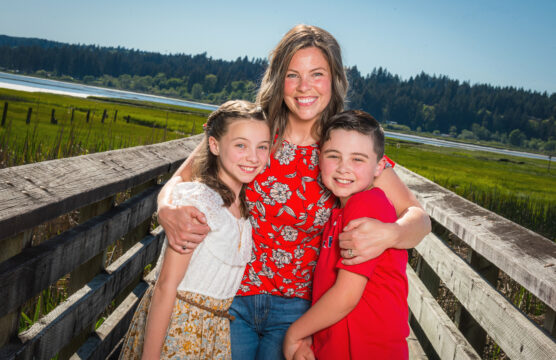 A mother and two children smiling on the boardwalk