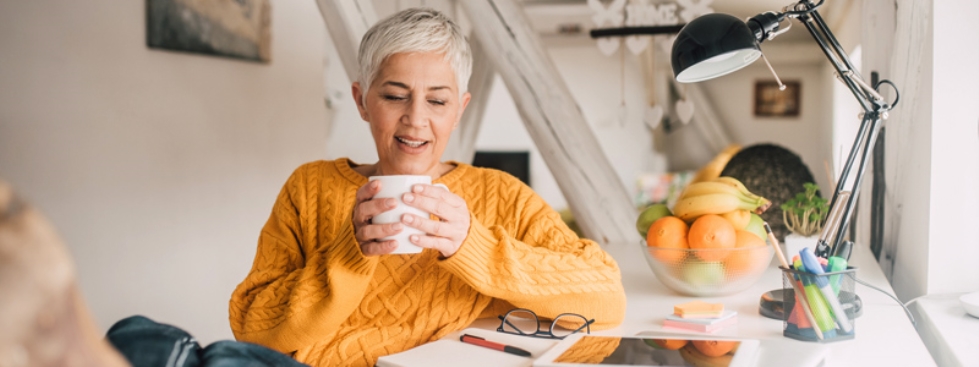 A woman reviewing paperwork and drinking coffee