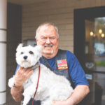 Man outside of a branch holding a dog