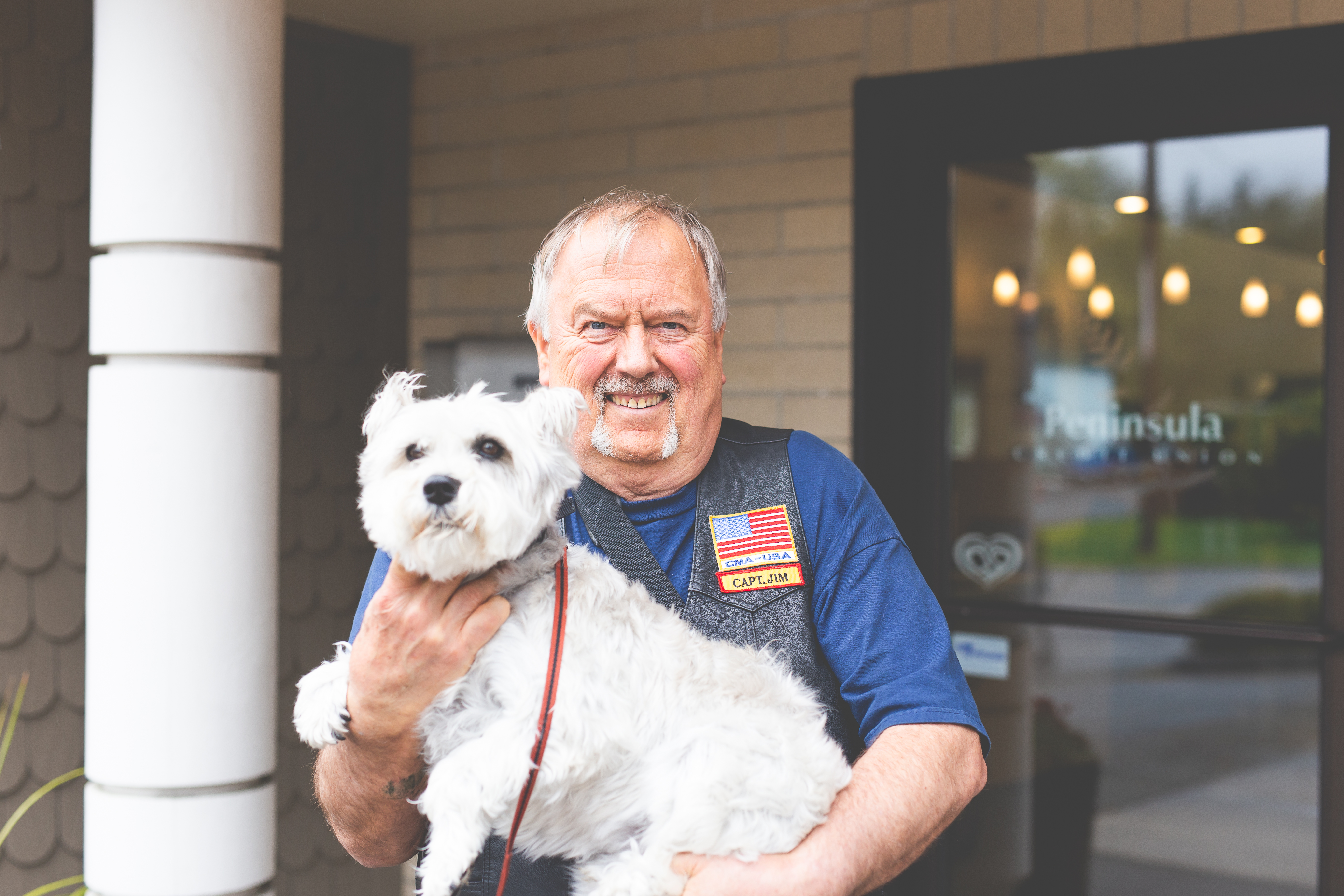 Man outside of a branch holding a dog