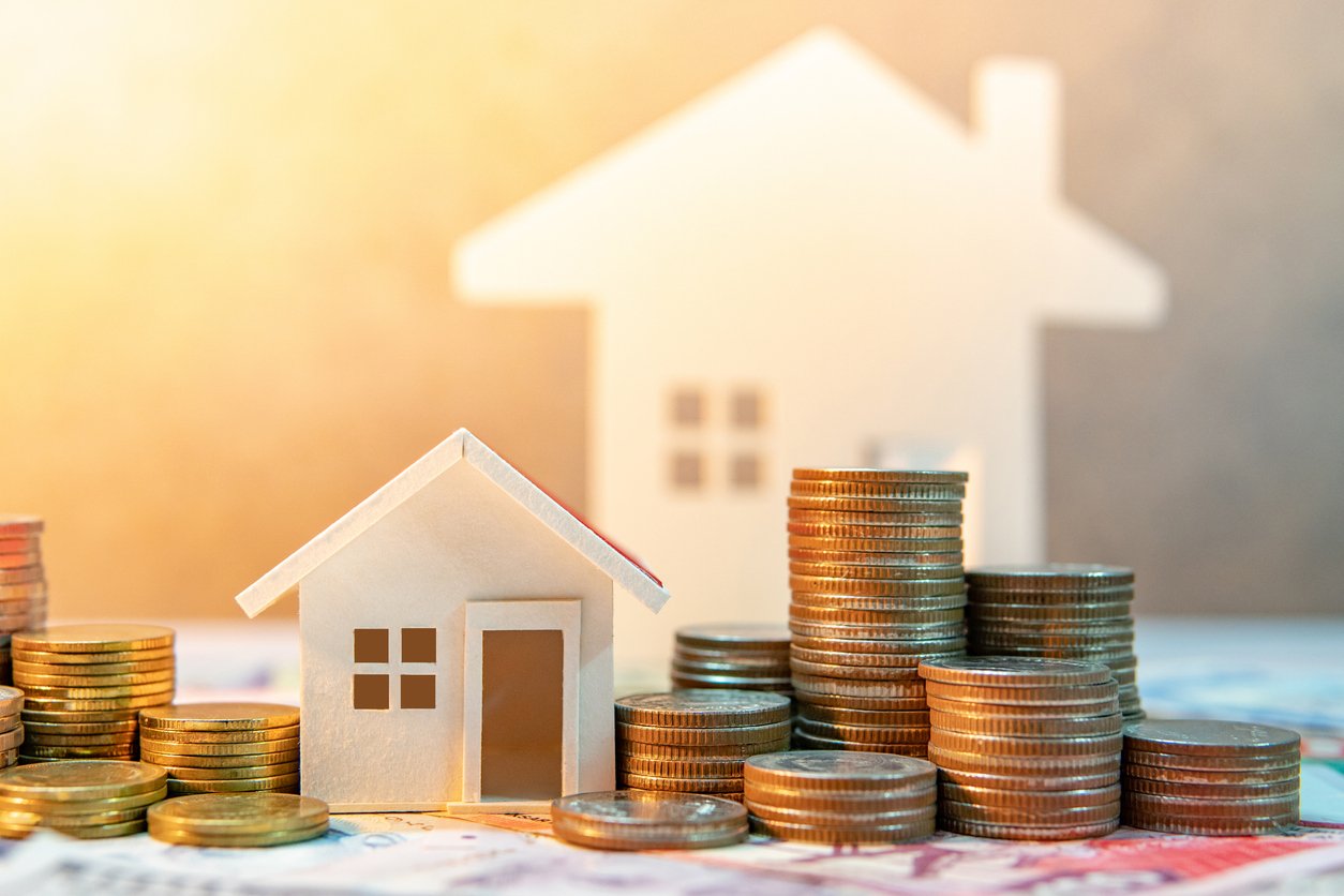 Paper houses with stacks of coins around them