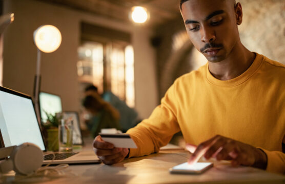 Young man using credit cart and mobile phone while checking his online bank account