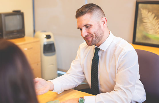 Smiling man in a necktie behind a desk
