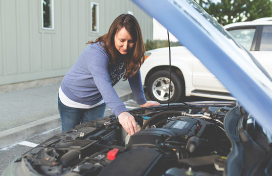 Woman working under the hood of a car