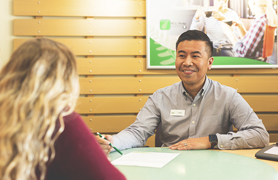 Smiling man sits at a desk with a woman and a form