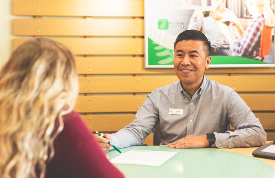 Smiling man sits at a desk with a woman and a form