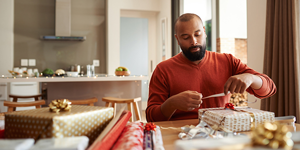 A man wrapping Christmas presents at home