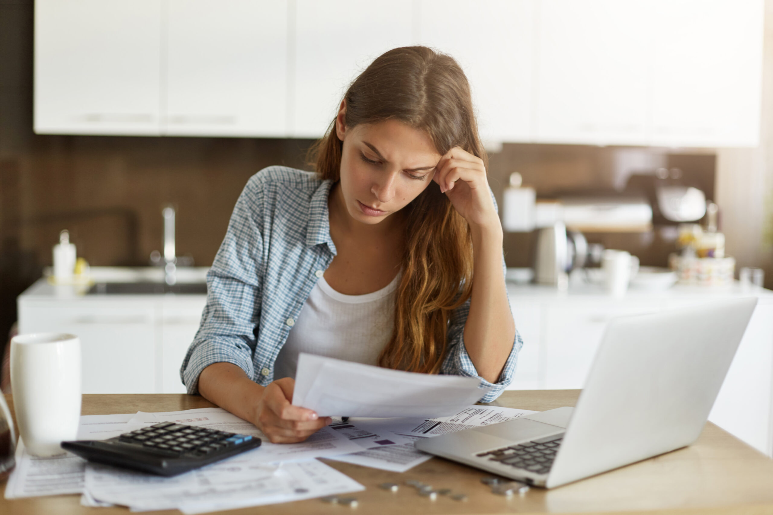 A woman looking at financial paperwork with a concerned look on her face